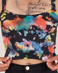 Front close up of Cropped Cami in Rainbow Magic Waters. Jesse is holding the bottom hem of Cami.