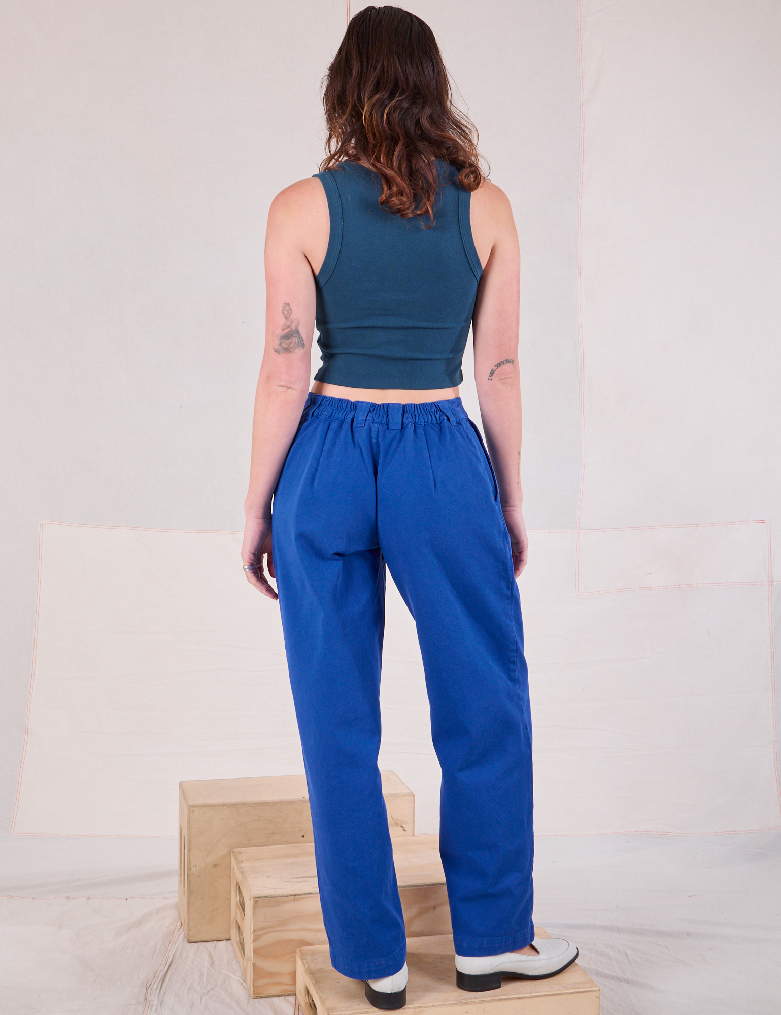 Back view of Mid-Rise Pleated Trousers in Royal Blue and lagoon Cropped Tank on Alex