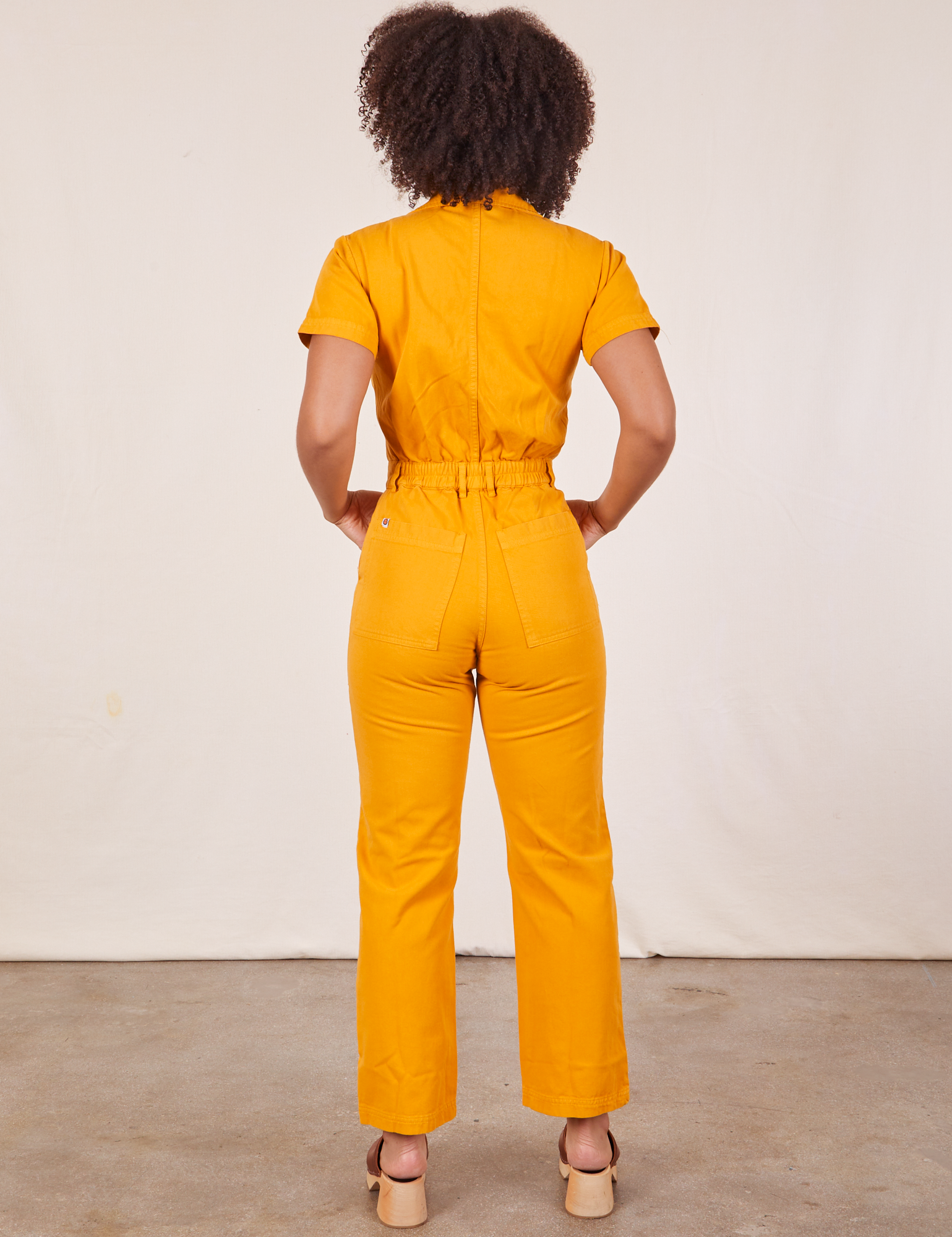 Back view of Short Sleeve Jumpsuit in Mustard Yellow worn by Gabi