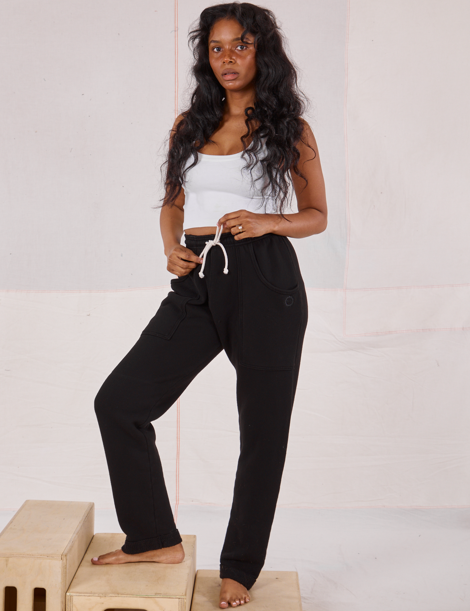 Kandia is 5&#39;3&quot; and wearing P Rolled Cuff Sweat Pants in Basic Black paired with a vintage off-white Cropped Tank