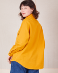 Angled back view of Flannel Overshirt in Mustard Yellow on Alex