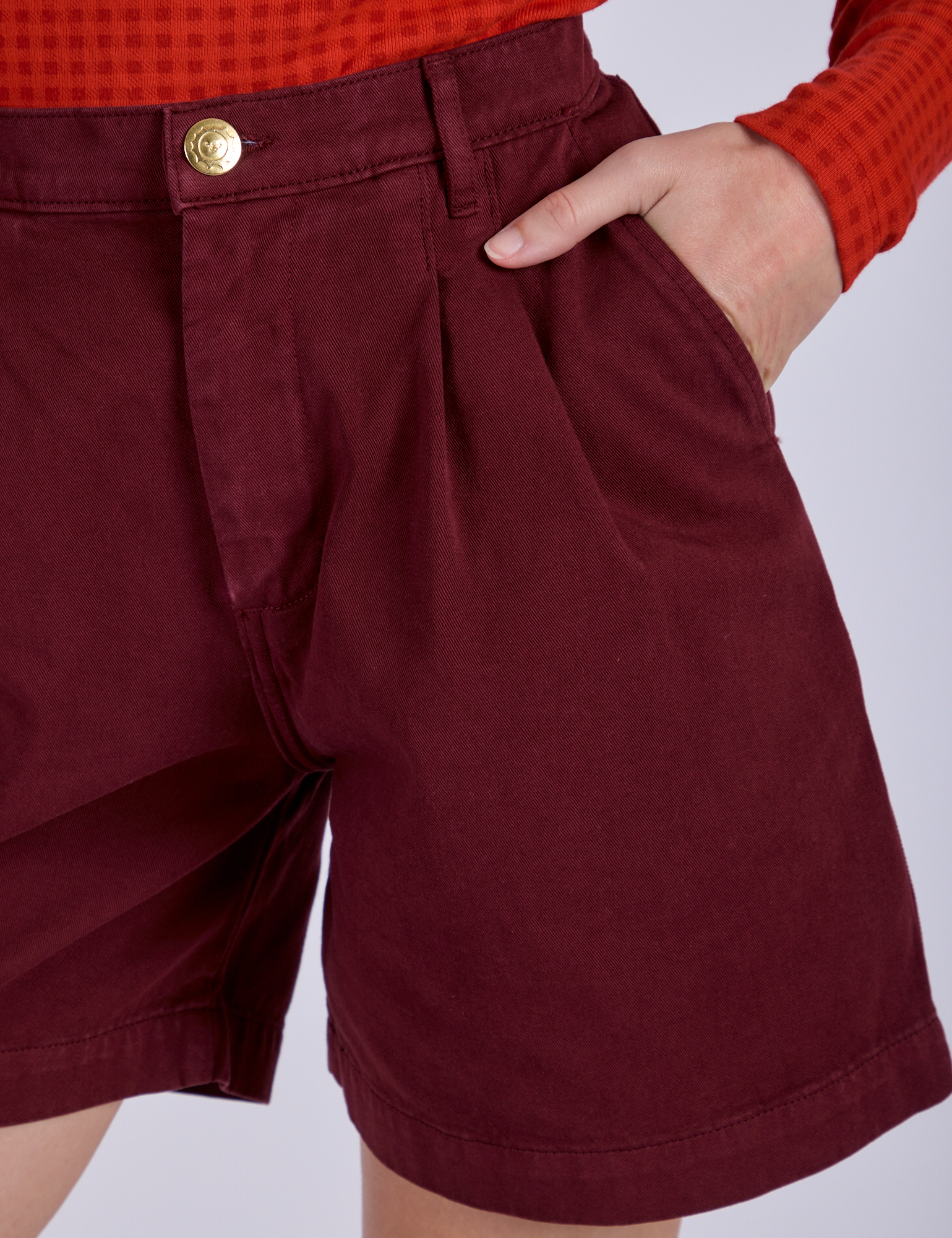 Close up of Alex's hand in the front pocket of Pleated Trouser Shorts in Red Wine
