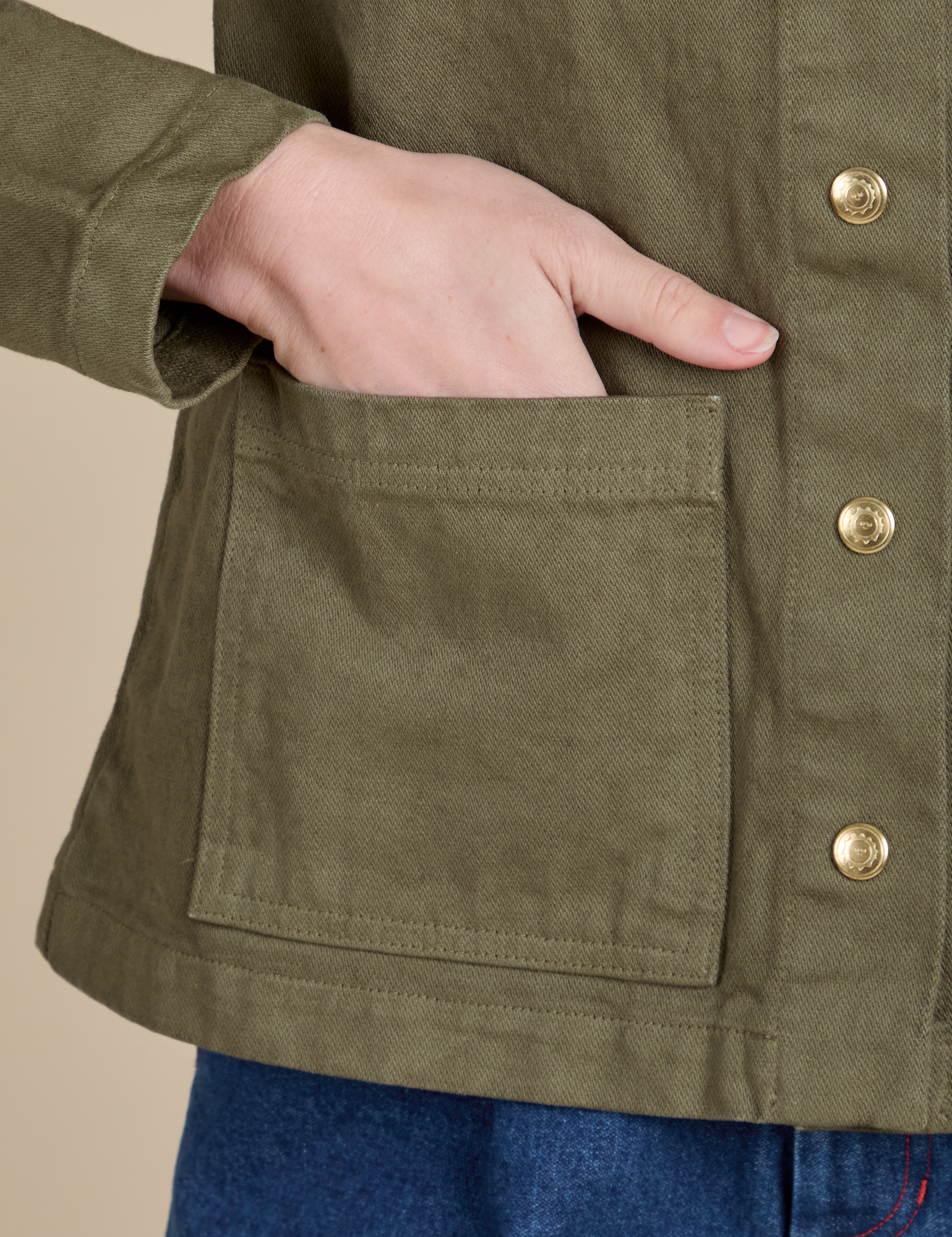 Close up of Alex&#39;s hand in the front pocket of Denim Work Jacket in Surplus Green