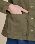 Close up of Alex's hand in the front pocket of Denim Work Jacket in Surplus Green