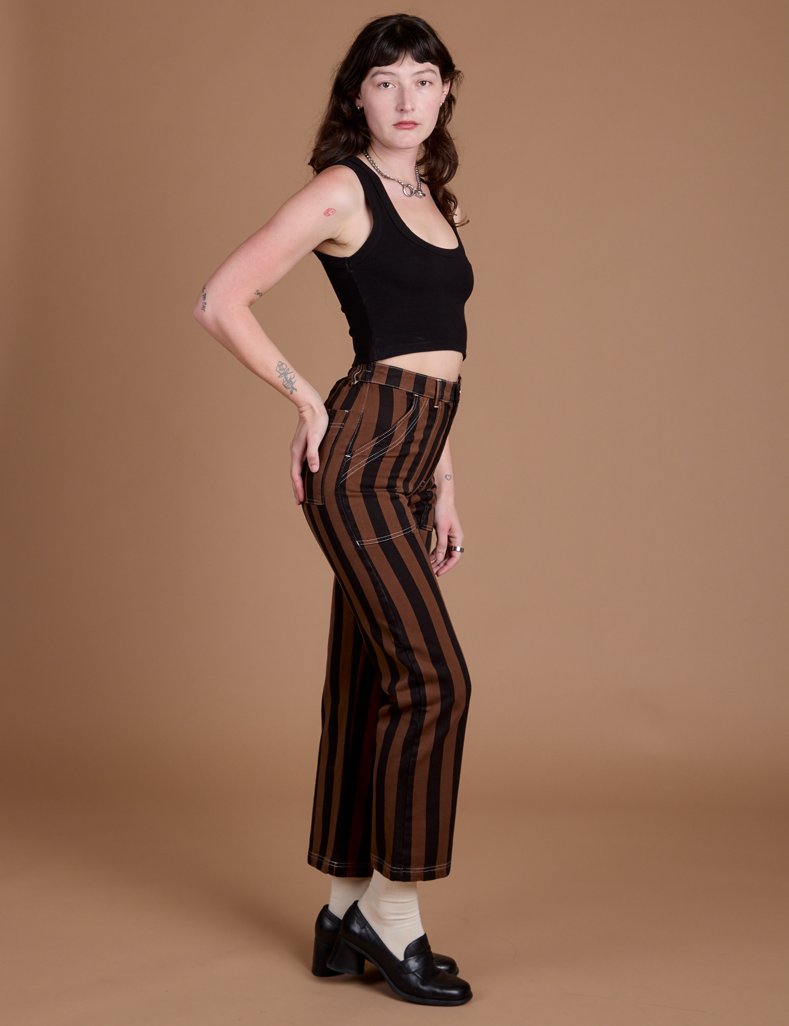 Side view of Black Stripe Work Pants in Fudgesicle Brown and black Cropped Tank on Alex