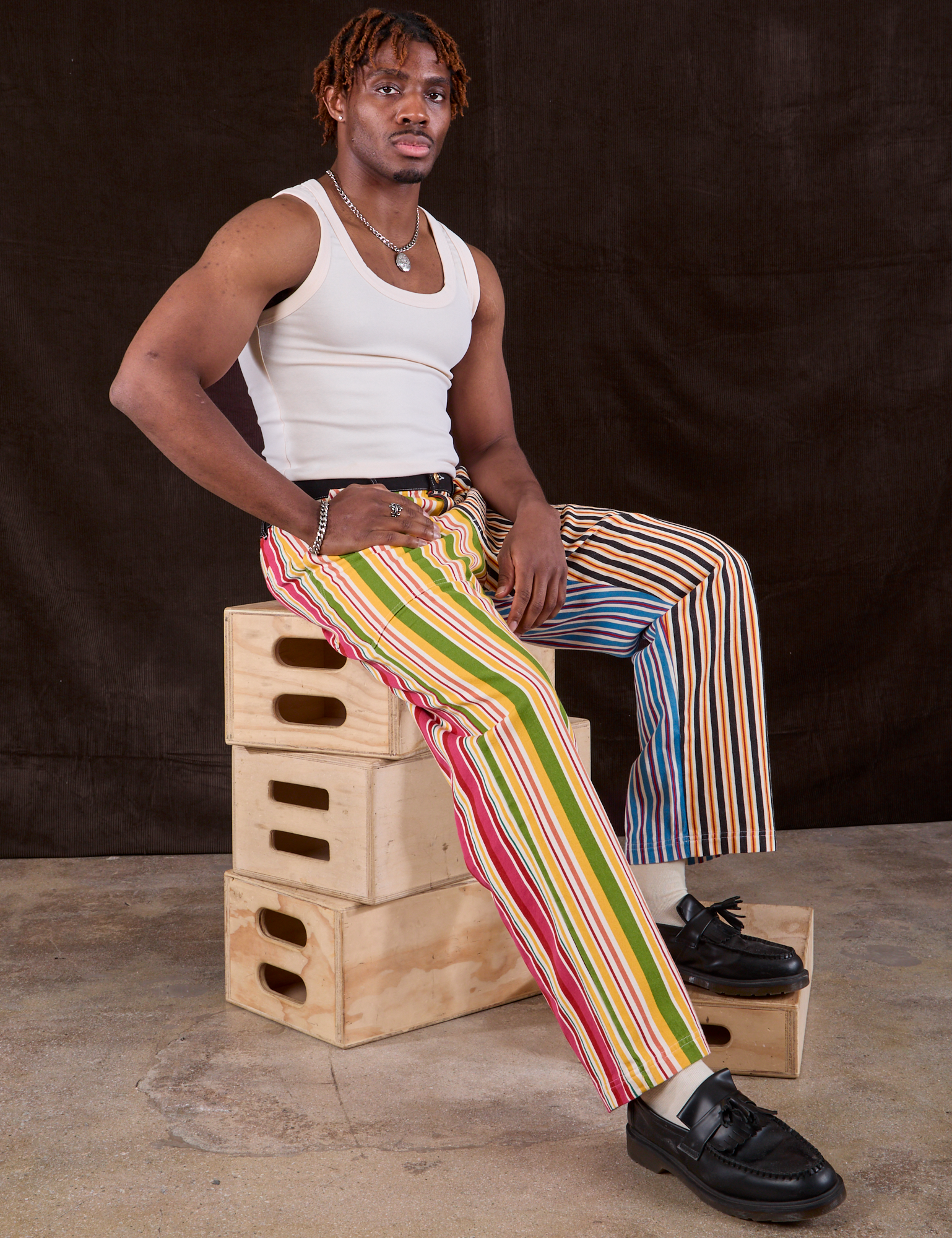 Mixed Stripe Work Pants worn by Isaac sitting on a stack of wooden crates