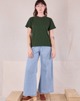 Alex is wearing Burly Tee in Swamp Green paired with light wash Denim Wide Leg Trousers