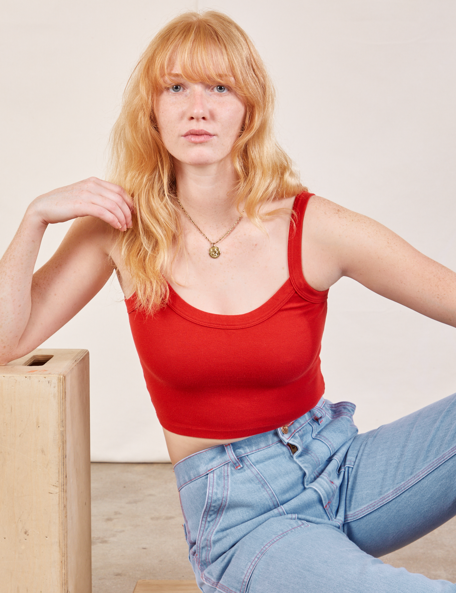 Margaret is wearing Cropped Cami in Mustang Red and light wash Carpenter Jeans