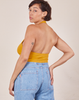 Back view of Halter Top in Mustard Yellow and light wash Sailor Jeans worn by Tiara