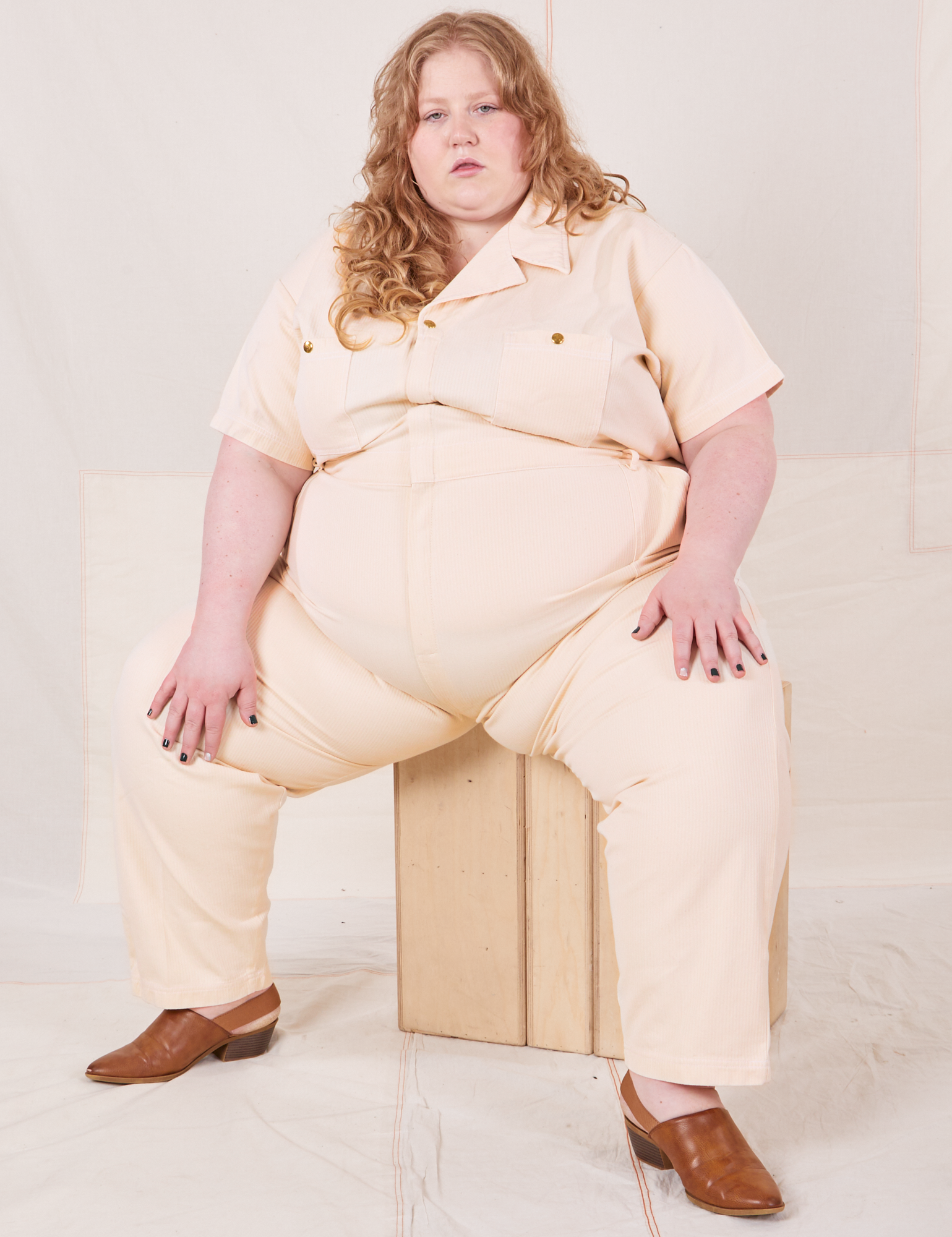 Heritage Short Sleeve Jumpsuit in Natural on Catie sitting on wooden crates