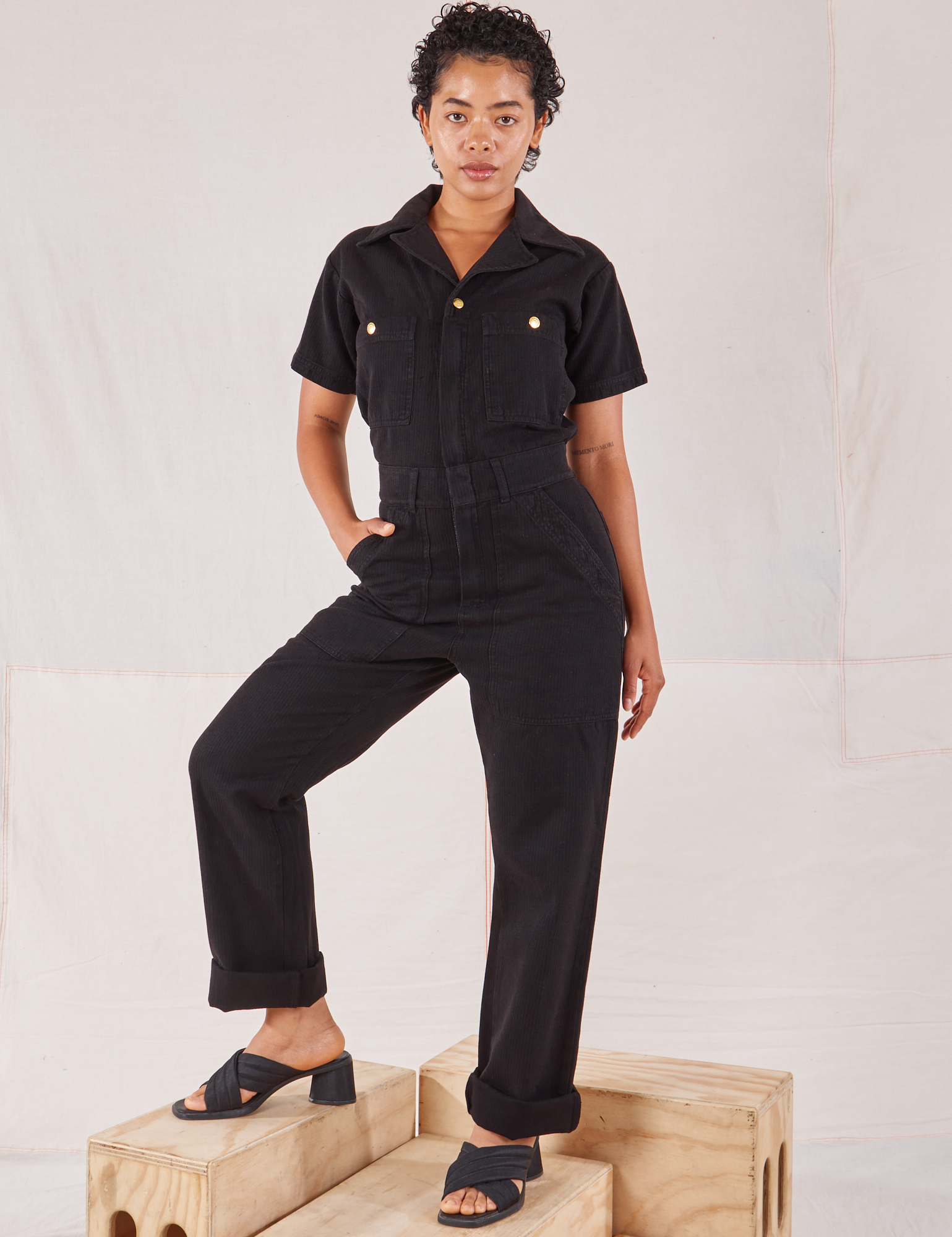 Mika is 5’1” and wearing XXS Heritage Short Sleeve Jumpsuit in Basic Black