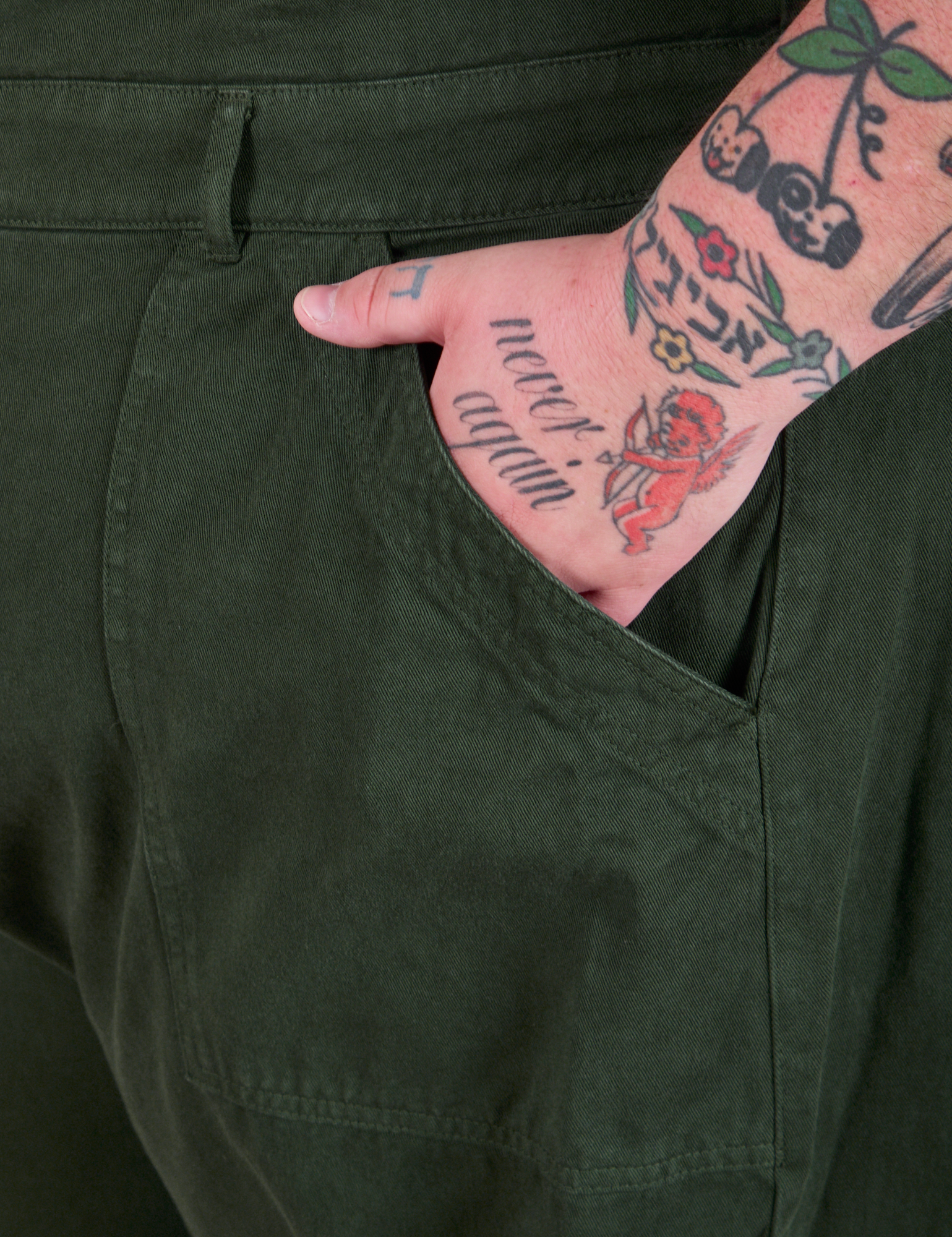 Close up of Sam&#39;s hand in the pocket of a Long Jumpsuit in Swamp Green