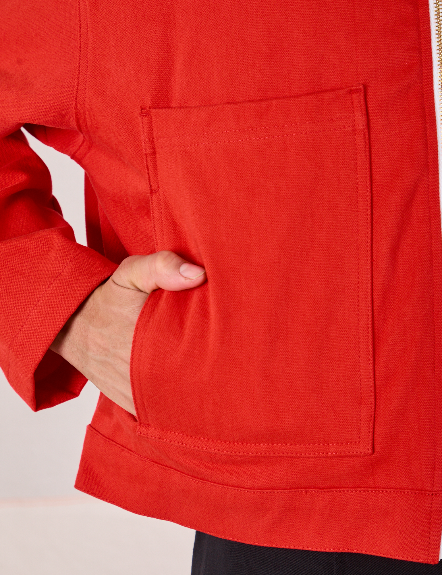Close up of Anthony&#39;s hand in the front pocket of Mechanic Jacket in Mustang Red