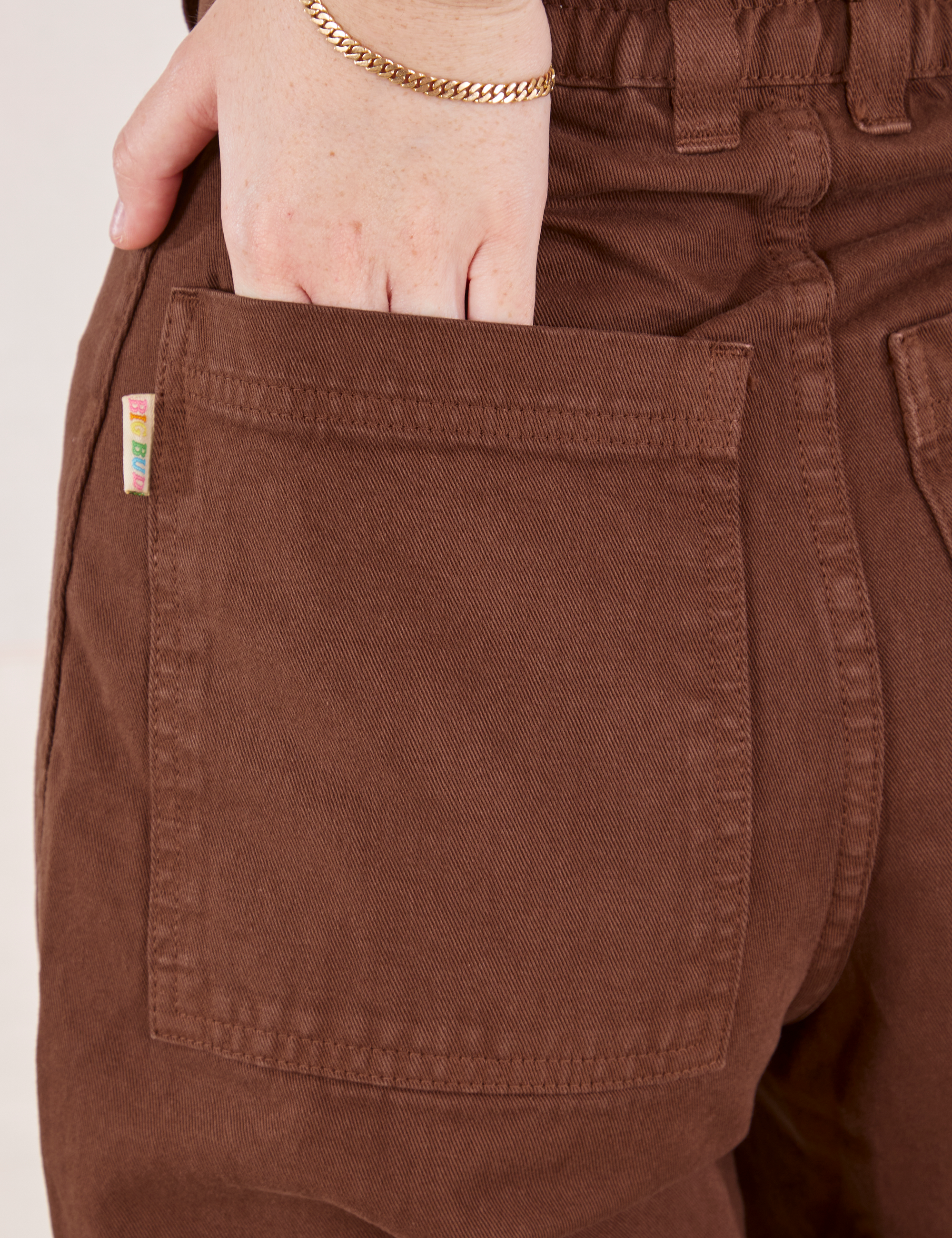 Petite Bell Bottoms in Fudgesicle Brown back pocket close up. Hana has her hand in the pocket.