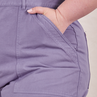 Front pocket close up of Petite Short Sleeve Jumpsuit in Faded Grape. Ashley has her hand in the pocket.