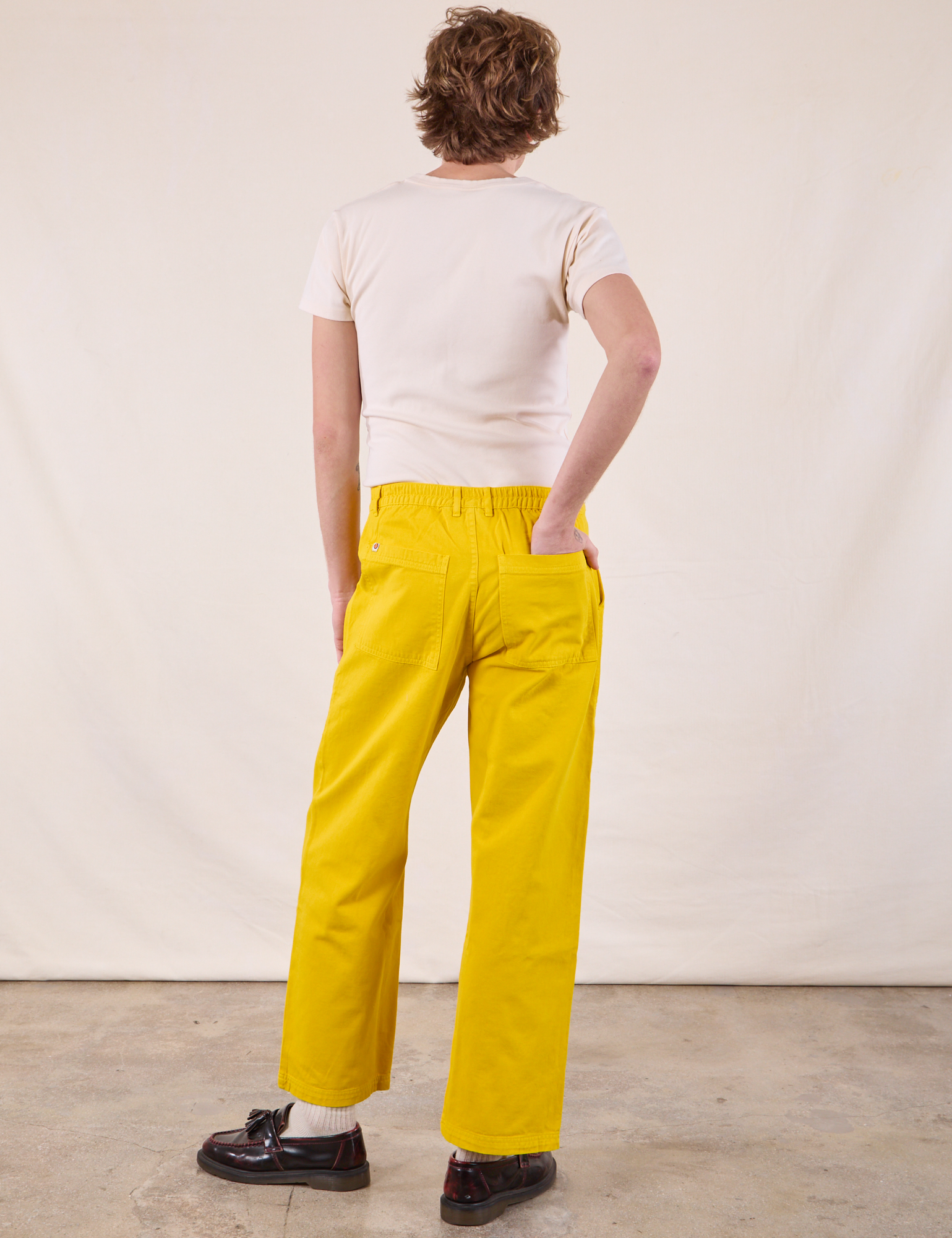 Back view of Work Pants in Golden Yellow and Burly Tee in Vintage Tee Off-White on Quinn