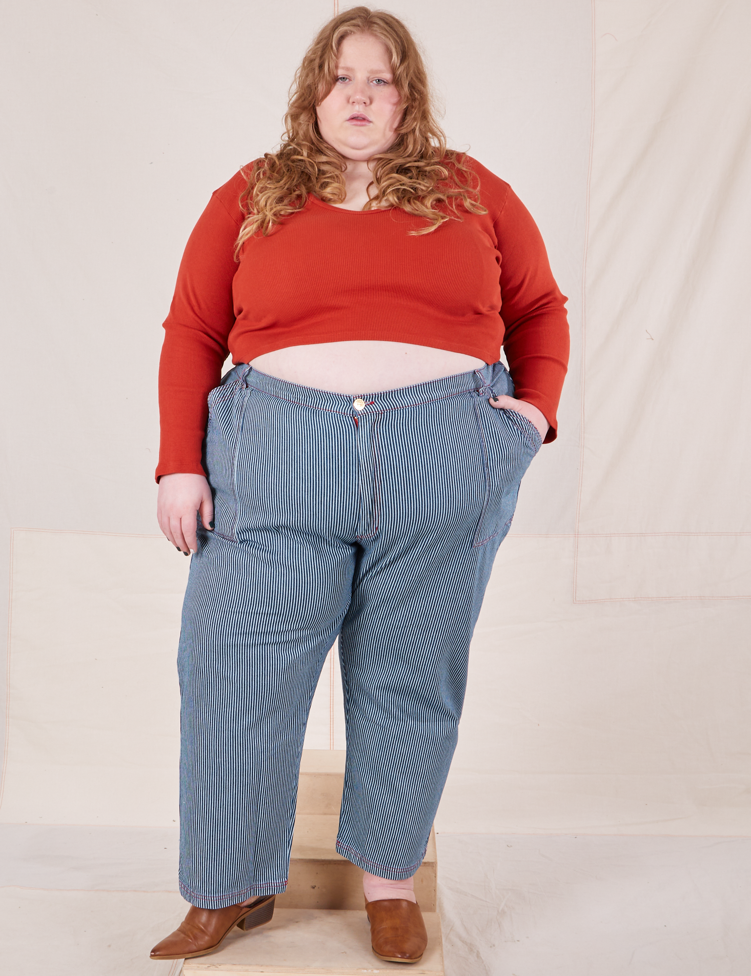 Catie is 5&#39;11&quot; and wearing 5XL Railroad Stripe Denim Work Pants paired with a paprika Long Sleeve V-Neck Tee