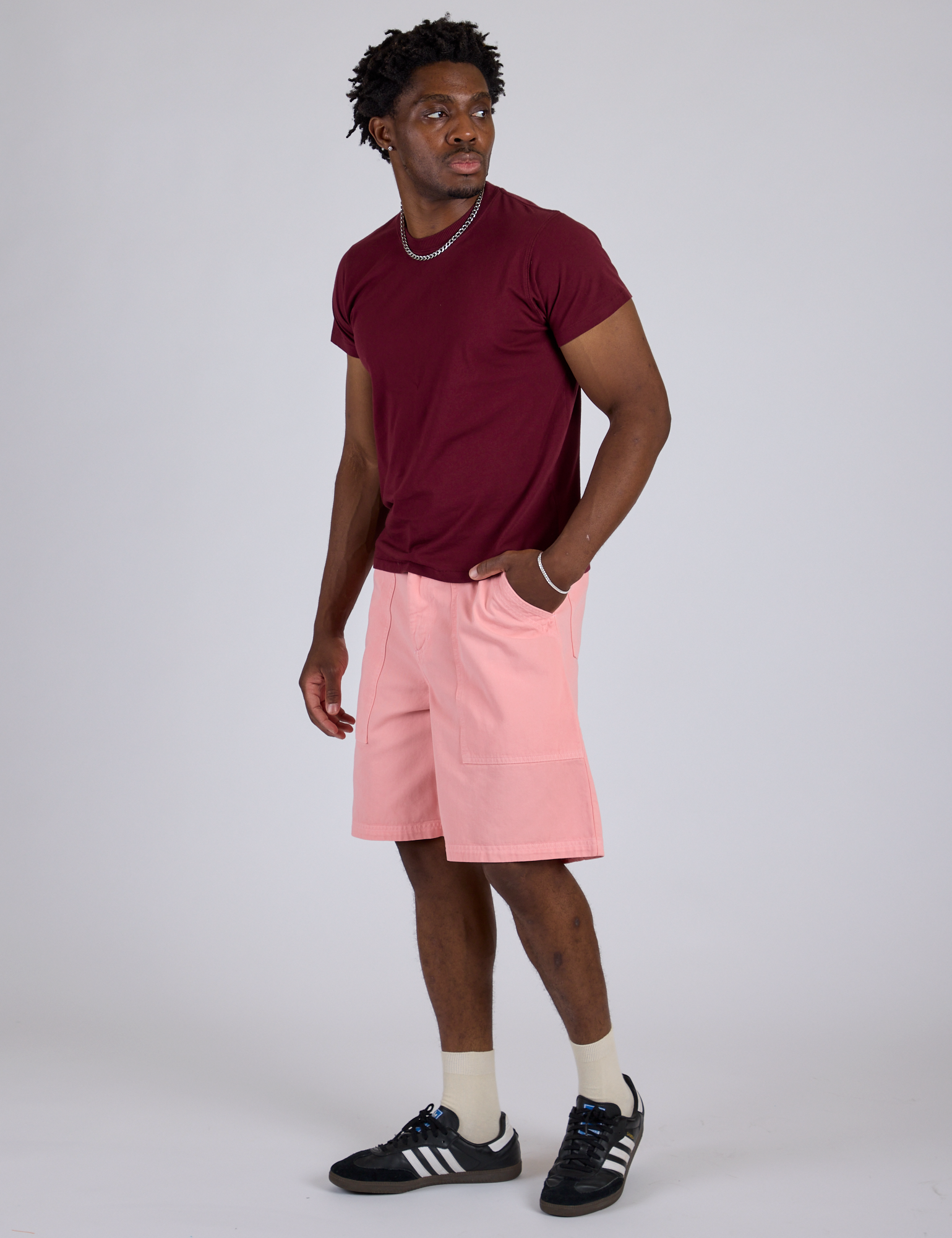 Angled front view of Longline Work Shorts in Baby Pink and red wine Organic Vintage Tee on Isaac