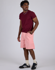 Angled front view of Longline Work Shorts in Baby Pink and red wine Organic Vintage Tee on Isaac