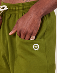 Lightweight Sweat Shorts in Summer Olive front pocket close up. Jerrod has their hand tucked into the pocket.