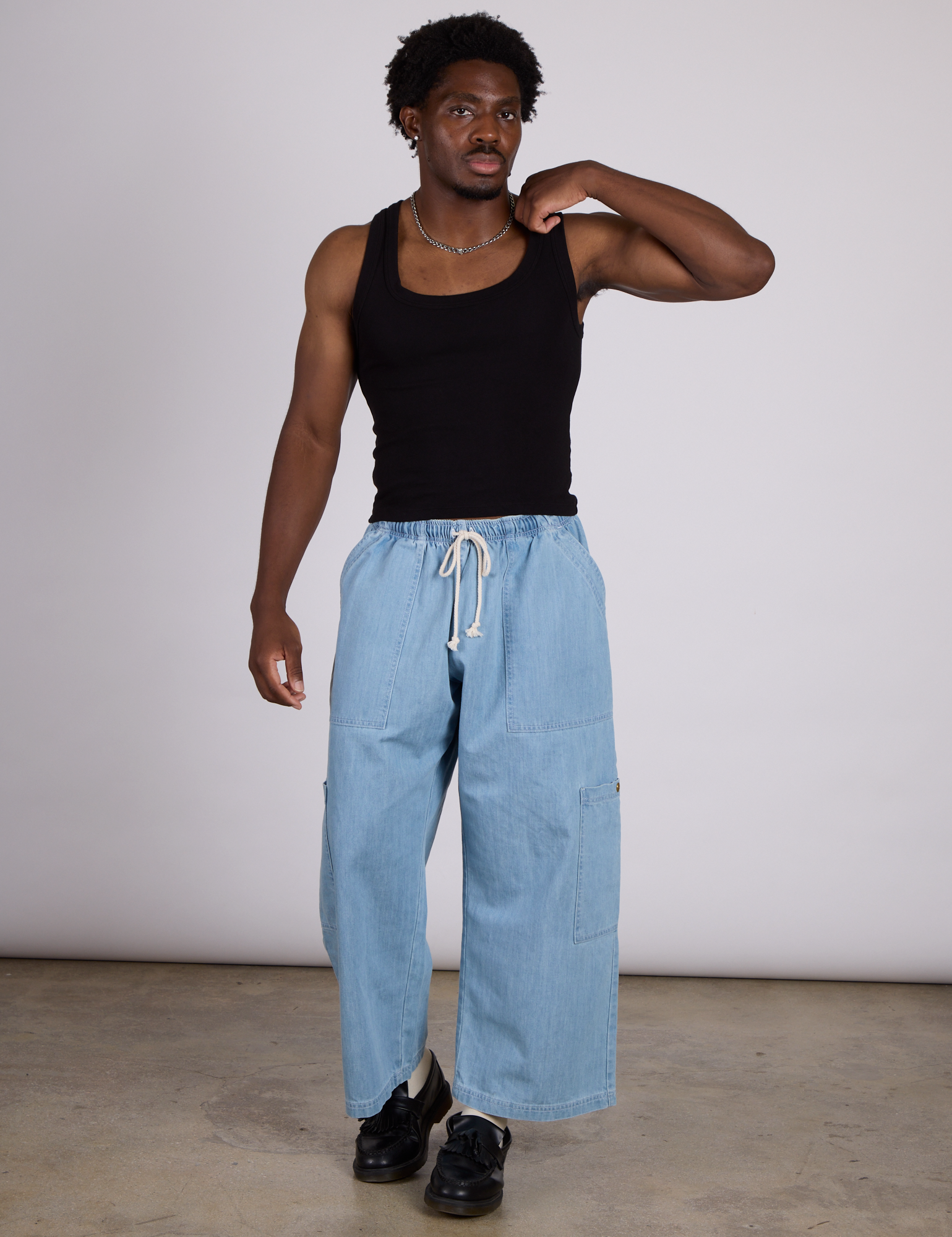 Isaac is wearing The Tank Top in Basic Black paired with light wash denim drop pocket pants