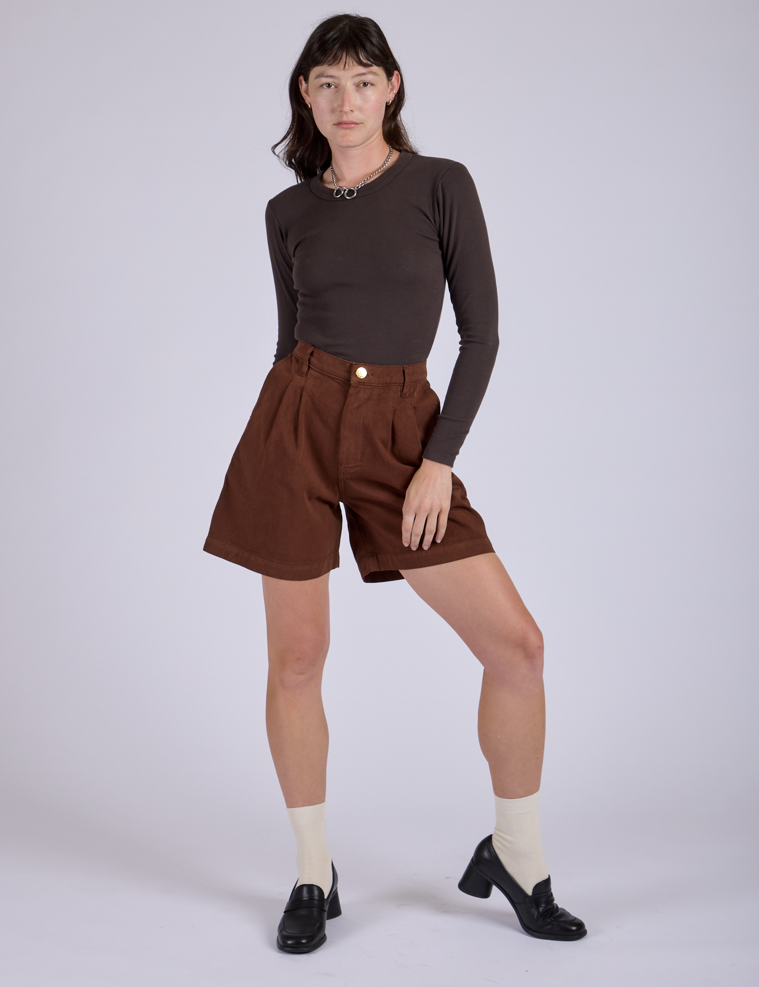 Alex is wearing Pleated Trouser Shorts in Fudgesicle Brown and Long Sleeve Baby Tee in Espresso