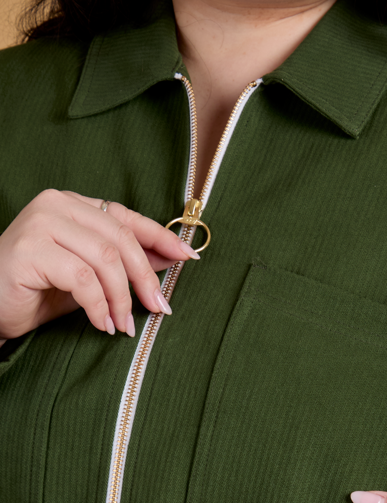 Front close up of Heritage Mechanic Jacket in Evergreen with Ashley pulling on the zipper pull ring