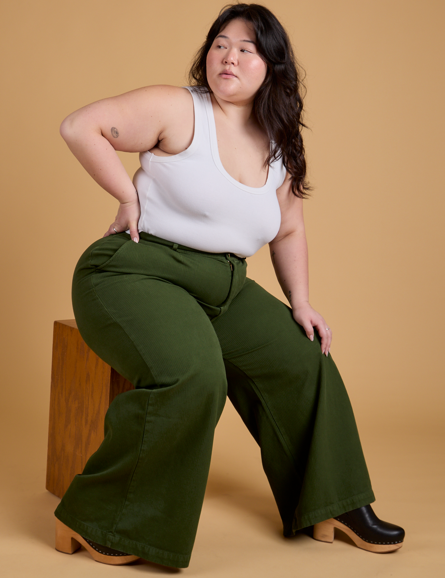 Ashley is wearing Heritage Wide Leg Trousers in Evergreen and vintage tee white Cropped Tank