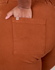 Close up of Morgan's hand in the back pocket of Western Pants in Burnt Terracotta