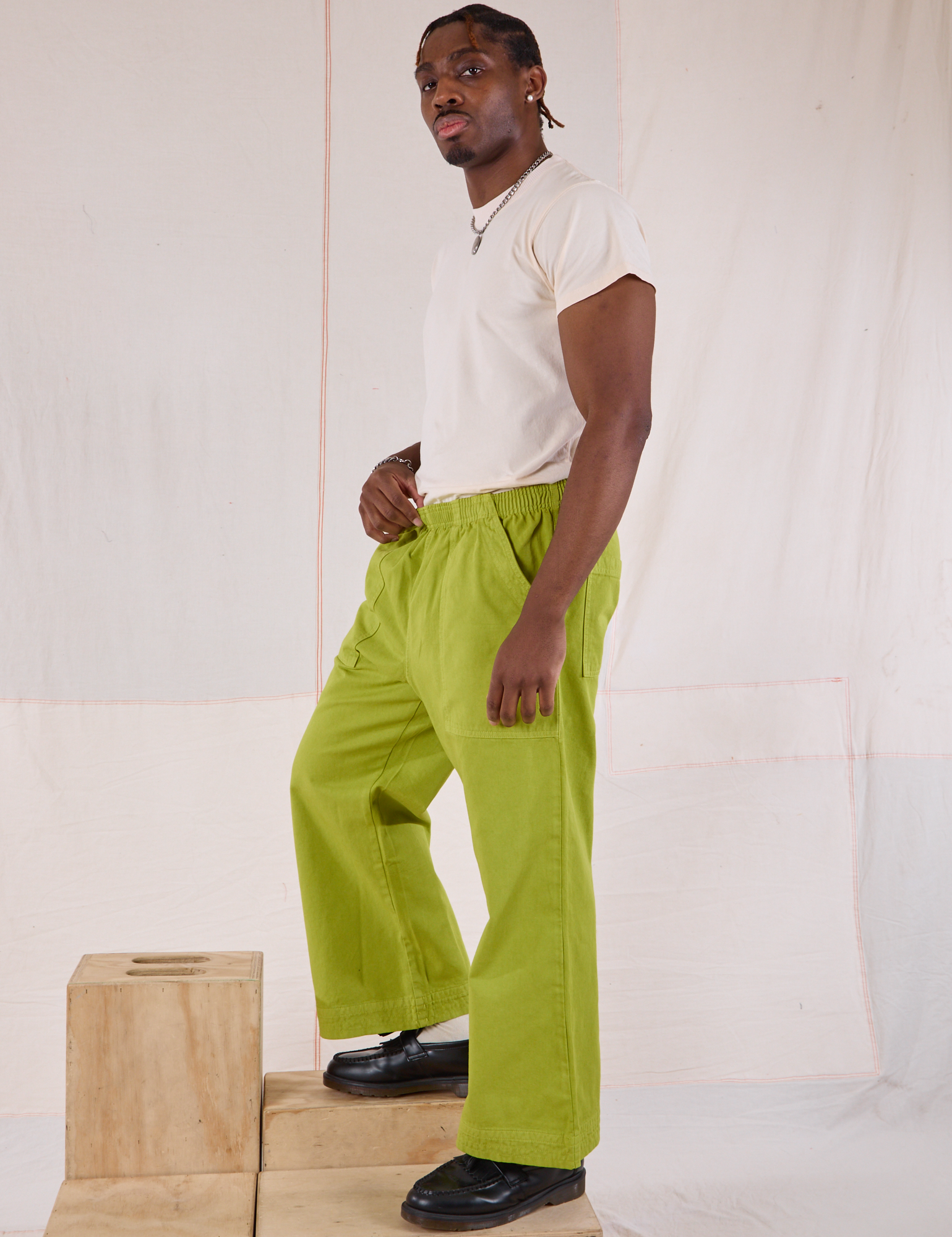 Side view of Action Pants in Gross Green and Organic Vintage Tee in Vintage Tee Off-White on Isaac