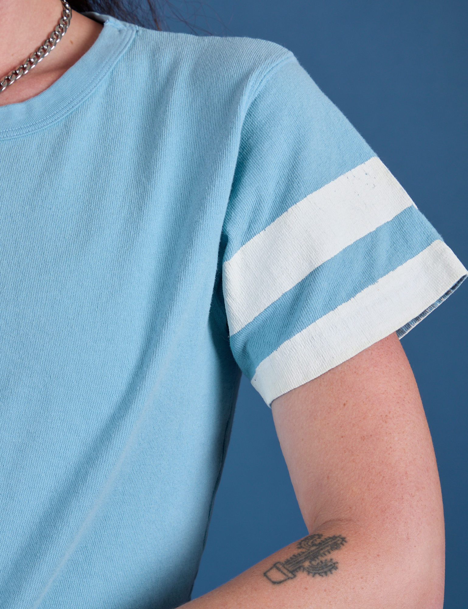 Painted Burly Tee in Baby Blue sleeve close up with two white painted stripes