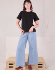 Alex is wearing Burly Tee in Basic Black paired with light wash Denim Wide Leg Trousers