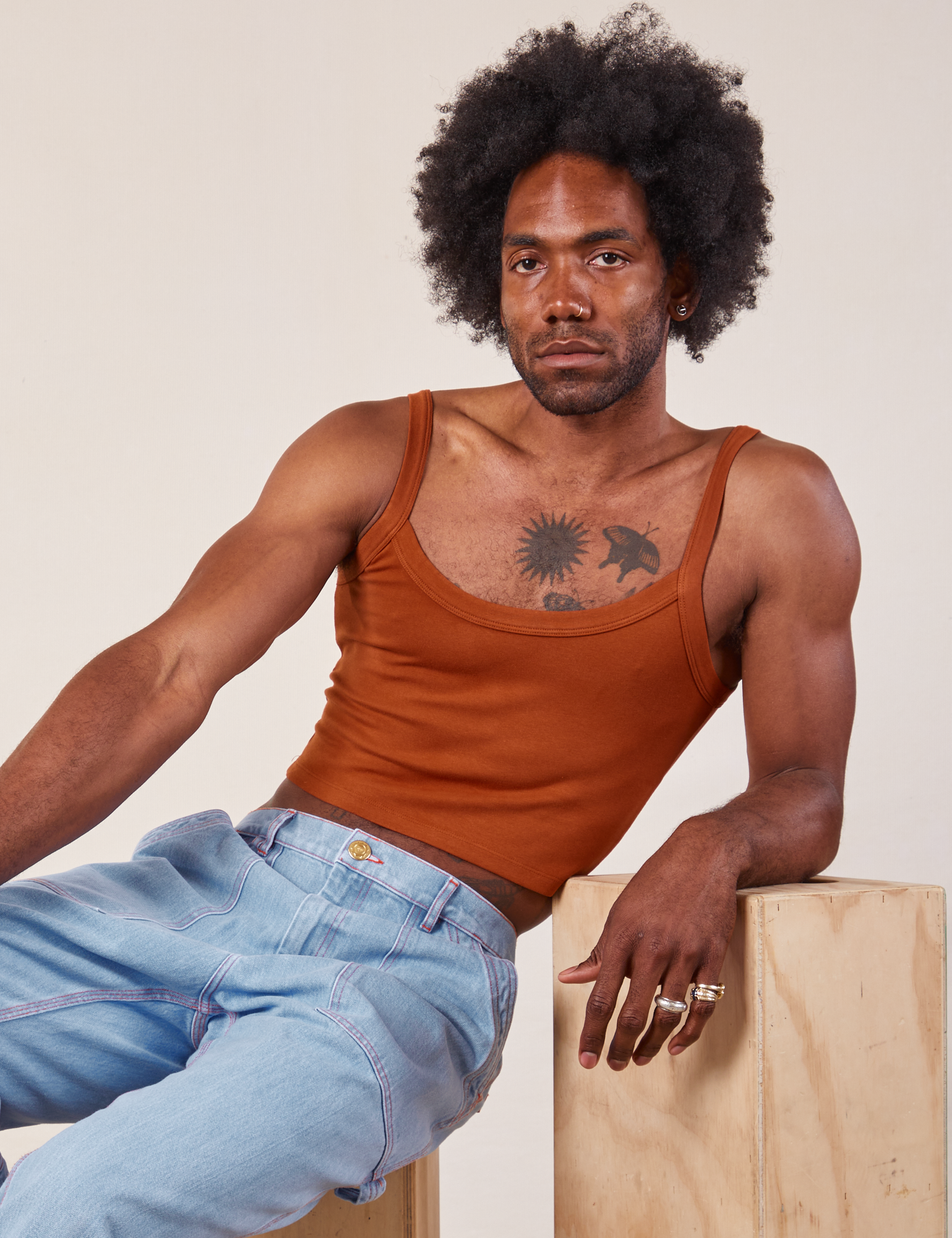 Jerrod is wearing Cropped Cami in Burnt Terracotta and light wash Carpenter Jeans