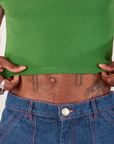 Cropped Cami in Lawn Green front close up. Jerrod is holding the edge of the hem.