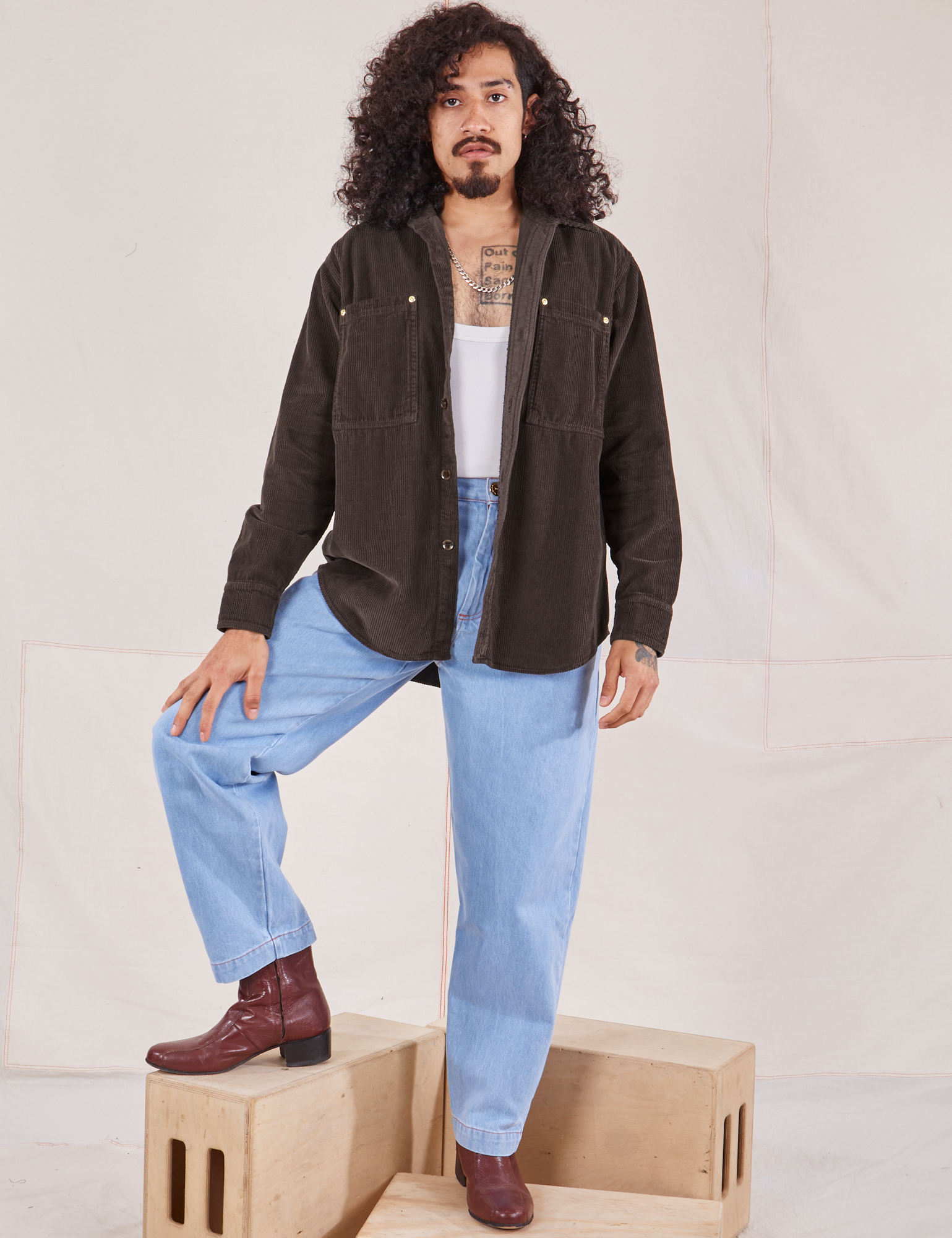 Jesse is wearing Corduroy Overshirt in Espresso Brown with a vintage off-white Cropped Tank Top underneath and light wash Denim Trouser Jeans