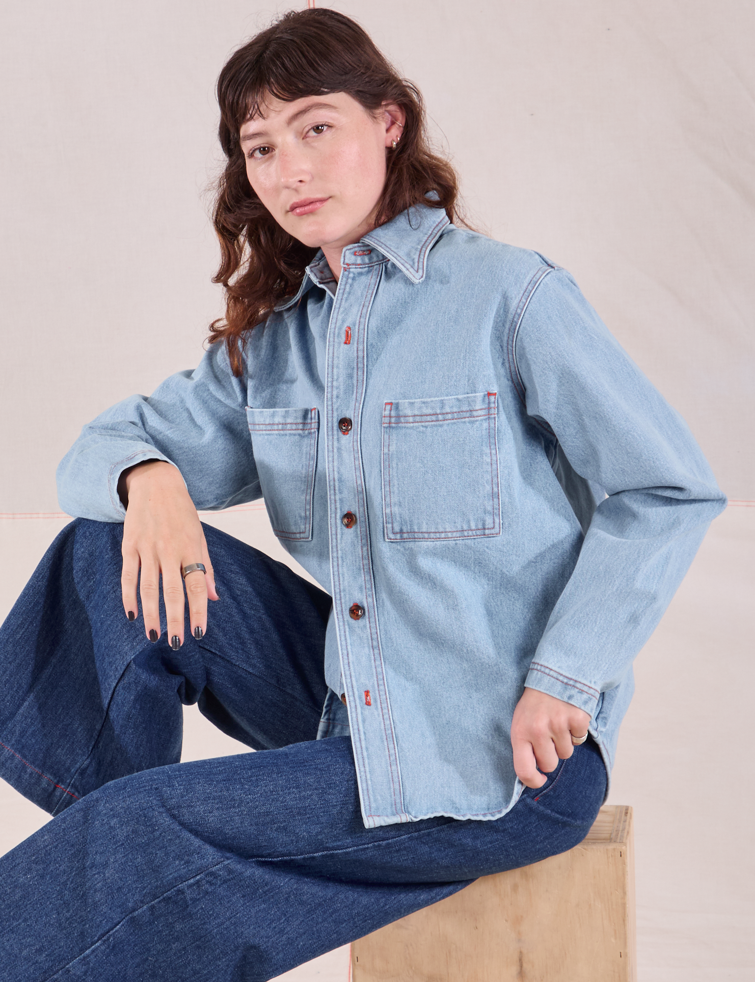 Alex is wearing a buttoned up Denim Overshirt in Light Wash