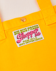 Sun Baby brass snap on Sunshine Yellow Shopper Tote Bag. Bag label in green and pink text that reads "Big Bud Press, Shopper Tote, Made in L.A., 100% Cotton Denim" on a white background