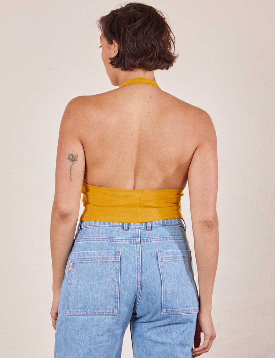 Back view of Halter Top in Mustard Yellow and light wash Sailor Jeans worn by Tiara.