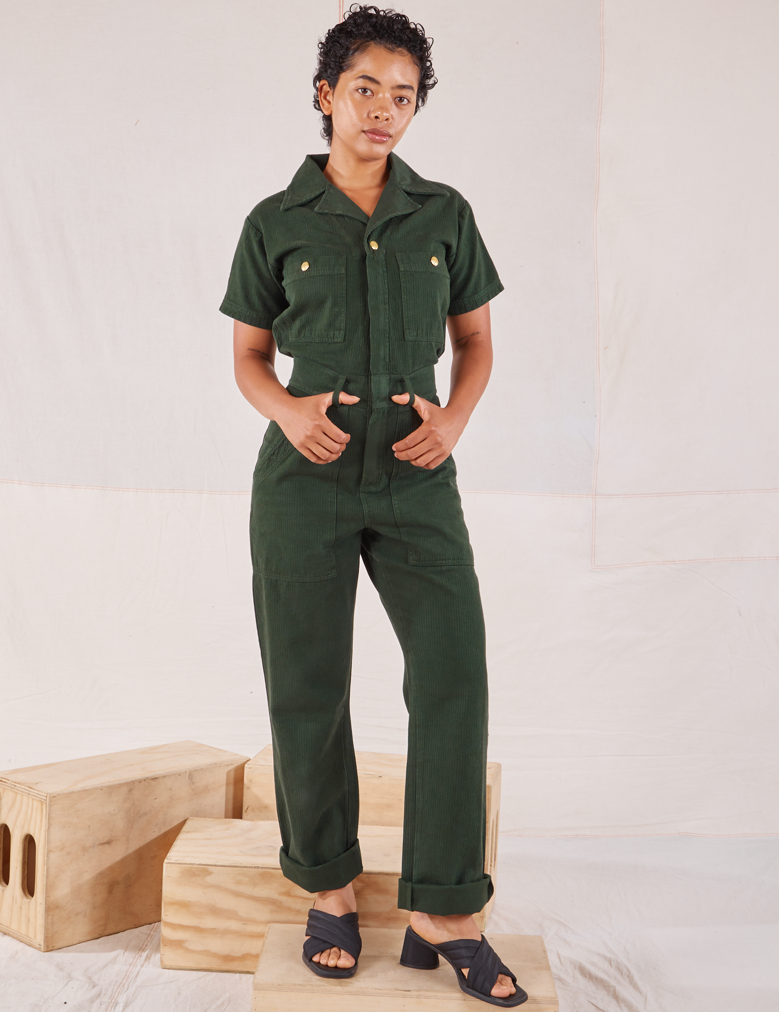 Mika is 5’1” and wearing XXS Heritage Short Sleeve Jumpsuit in Swamp Green