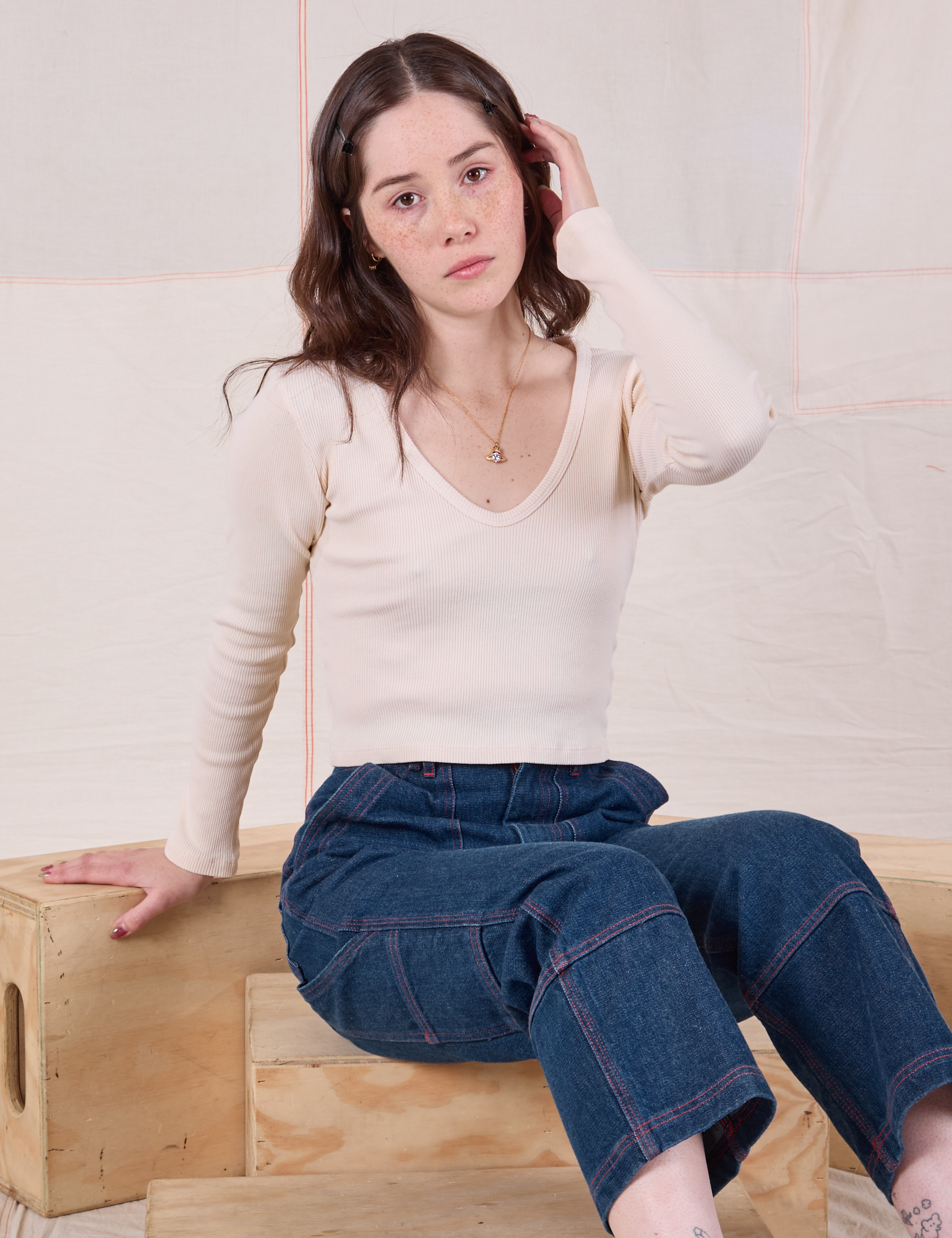 Hana is wearing Long Sleeve V-Neck Tee in Vintage Tee Off-White and dark wash Carpenter Jeans