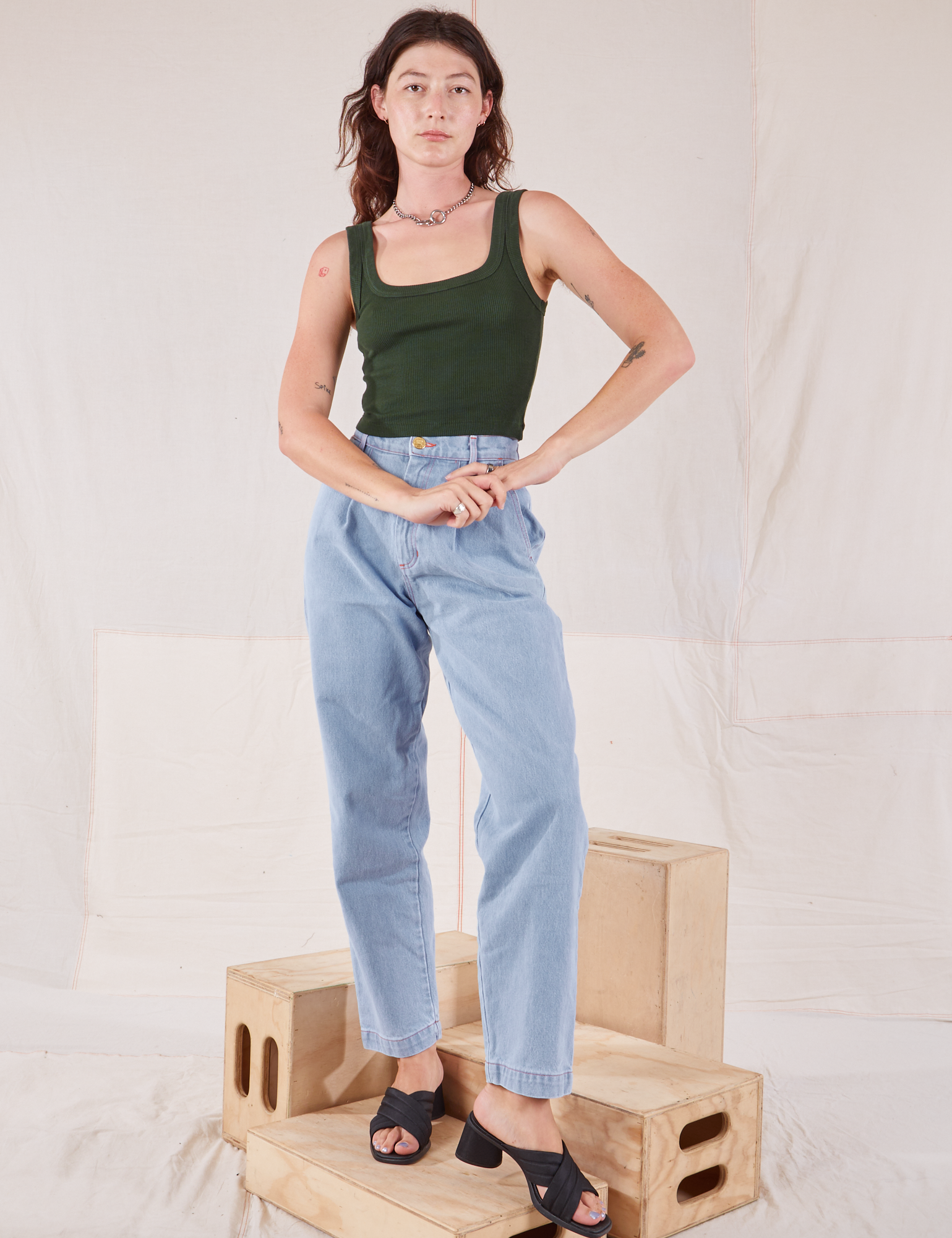 Alex is wearing Square Neck Tank in Swamp Green and light wash Denim Trousers