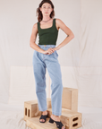 Alex is wearing Square Neck Tank in Swamp Green and light wash Denim Trousers