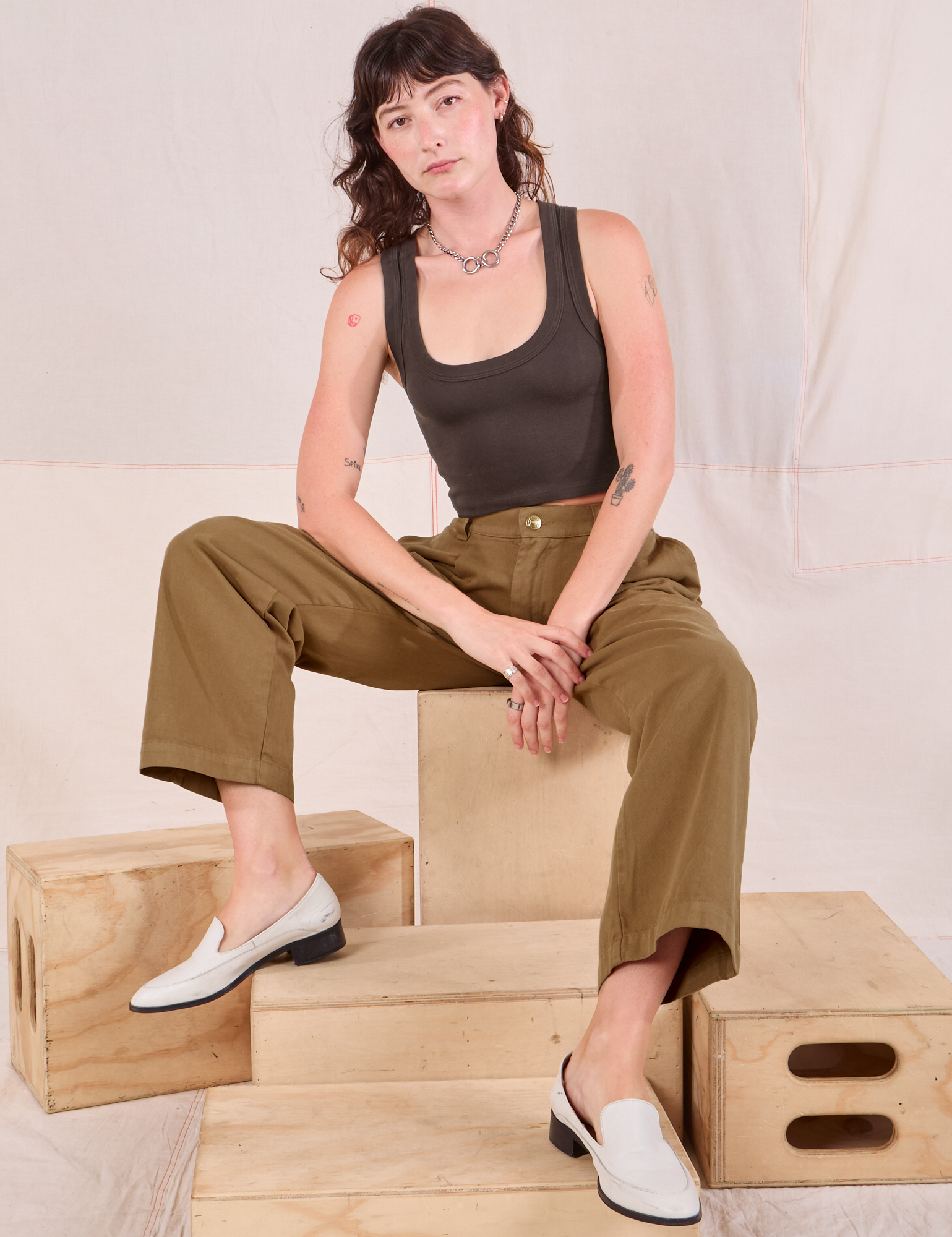 Alex is wearing Mid-Rise Pleated Trousers in Desert Brown and espresso brown Cropped Tank