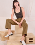 Alex is wearing Mid-Rise Pleated Trousers in Desert Brown and espresso brown Cropped Tank