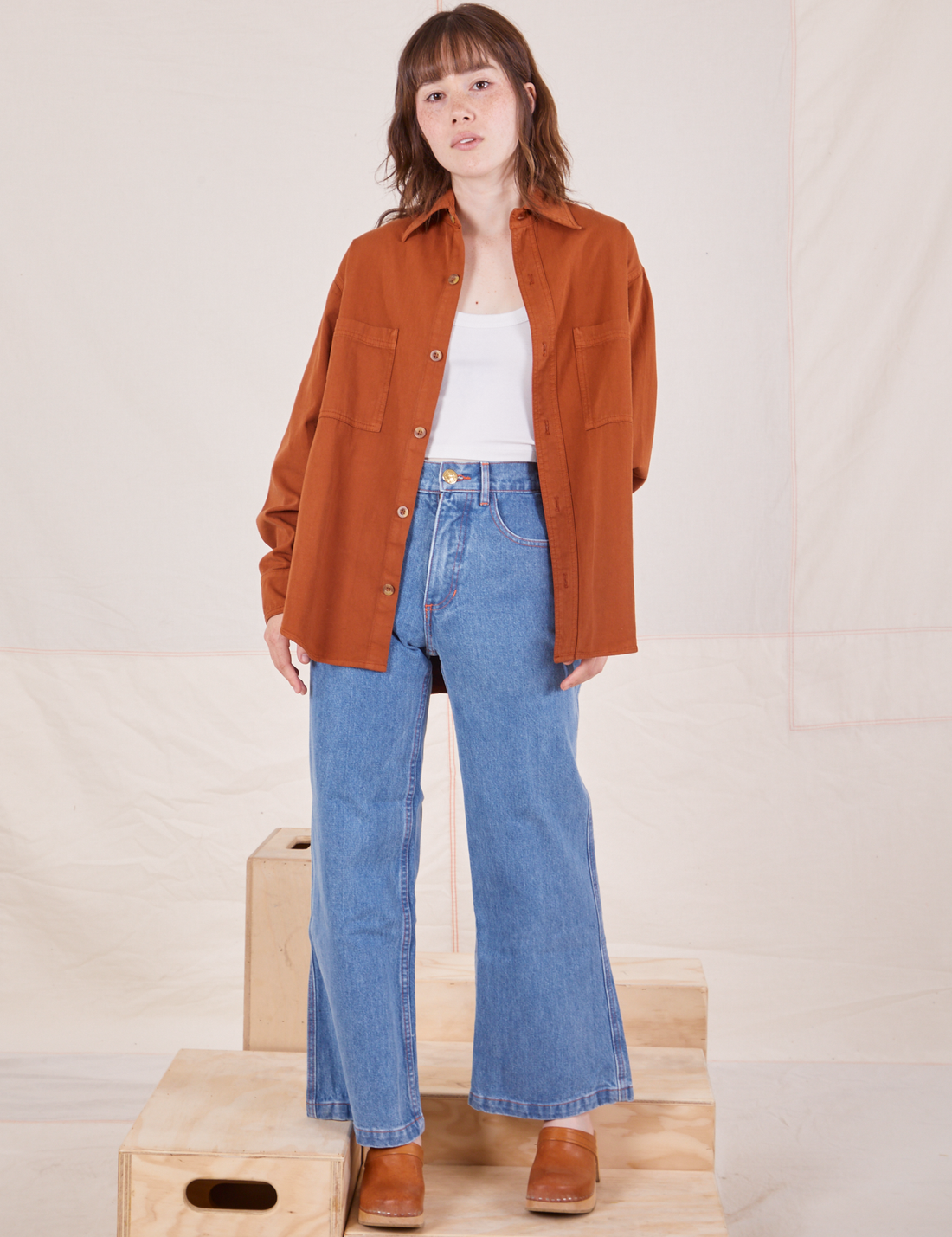 Hana is wearing Oversize Overshirt in Burnt Terracotta paired with vintage off-white Cropped Tank Top and light wash Sailor Jeans
