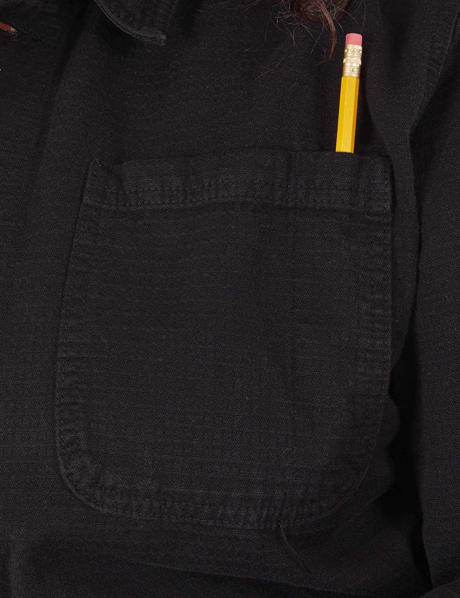 Field Coat in Basic Black front pocket close up. Pencil is in the pen pocket slot.
