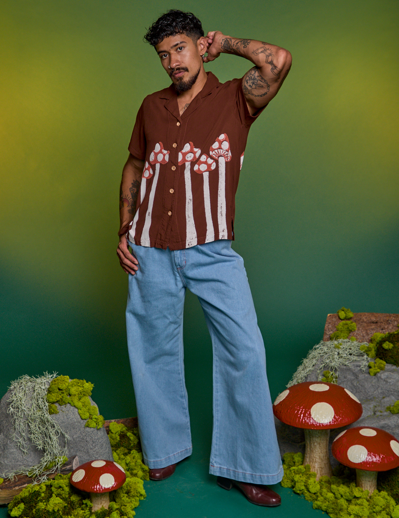 Jesse is wearing a buttoned up Paintstamped Pantry Button-Up in Mushroom paired with light wash Indigo Wide Leg Trousers