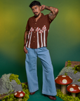 Jesse is wearing a buttoned up Paintstamped Pantry Button-Up in Mushroom paired with light wash Indigo Wide Leg Trousers