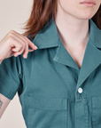 Upper front close up of Petite Short Sleeve Jumpsuit in Marine Blue. Hana is holding the point of a collar.