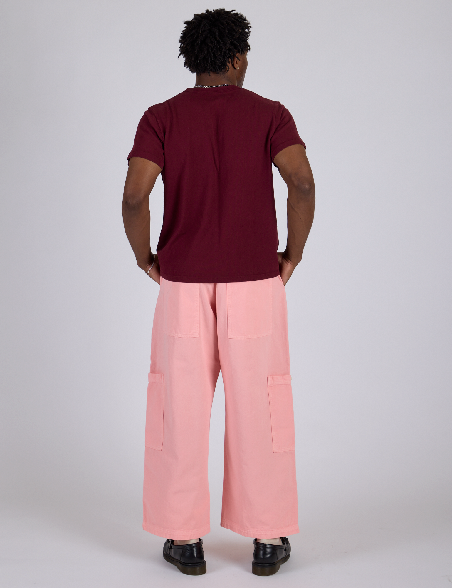 Back view of Drop Pocket Cargo Pants in Baby Pink and red wine Organic Vintage Tee on Isaac